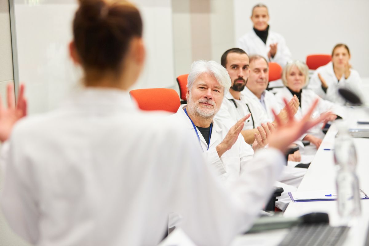 Platea di medici in camice applaude durante una lezione in aula